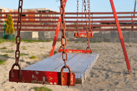 Old style playground swings with chains and wooden seatsの写真素材