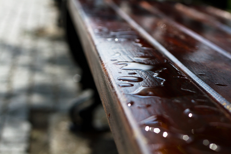 Close-up of raindrops on a brown benchの写真素材