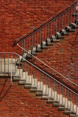 Vertical shot of outside steps against a brick wall, taken in sunshine.