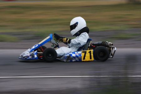 A panning technique shot of a speeding blue and silver cadet go kart with number 71 on the side pod.
