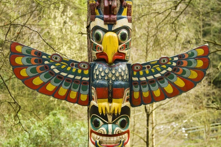 Section of a totem pole, a wooden structure featuring a bird with wings out.の写真素材