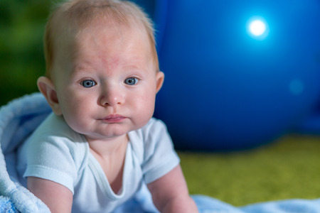 Close-up portrait of the baby. Blue ball on background.の写真素材