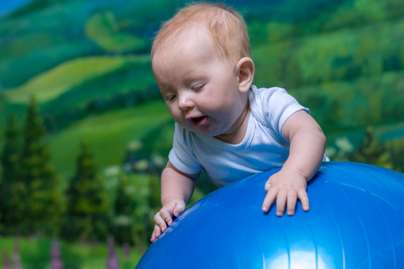 Portrait of a surprised child. Close-up portrait of the baby, on blue ball.の写真素材