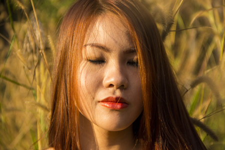 Asian girl with her eyes closed in a fieldの写真素材