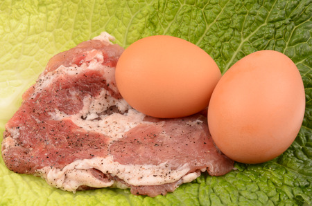 raw steak and egg on a leaf of cabbage closeupの写真素材