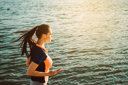 Fashion sport style female runner jogging over river water copysの写真素材