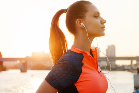Young female runner jogging over sunset,river side,urban city coの写真素材