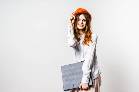 Portrait of young student of architecture holding folder and wearing red helmetの写真素材