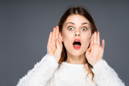 Shocked office girl eavesdropping. Hearing gesture shock emotion concept. Young nerdy stunned lady in glasses listening expressing disbelief gasping. Surprised faceの写真素材