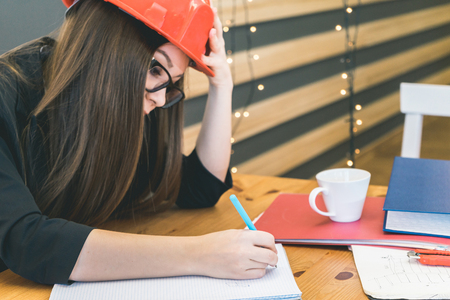 Thoughtful woman builder writing somethingの写真素材