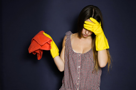 Tired girl holding the head.Headache after cleaning house or flatの写真素材