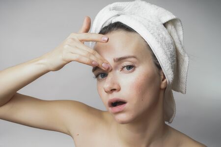Woman touch her face,looking for wrinkles. with a towel on her headの写真素材