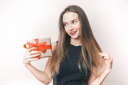 A girl with a gift looks to the left. Brunette with long hair. Isolated on white background