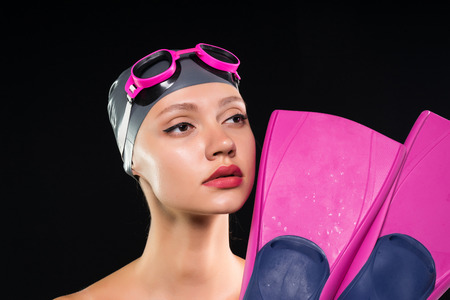 A woman a swimmer in a swimming cap and glasses thought about before the swim, holds the flippersの写真素材