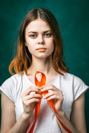 Portrait of a beautiful sad girl with a red ribbon in her hands. She looks at the cameraの写真素材