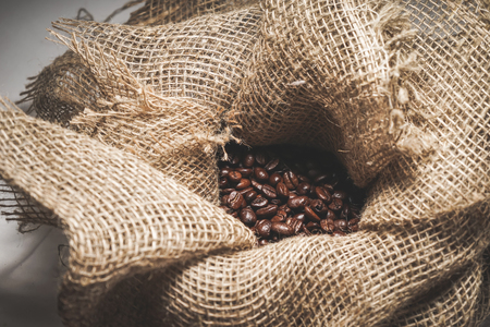 Grains of coffee in a cloth bag on a tableの写真素材