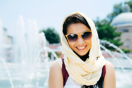 Portrait of a smiling dark-haired girl in sunglasses in Istanbul against the background of a fountainの写真素材