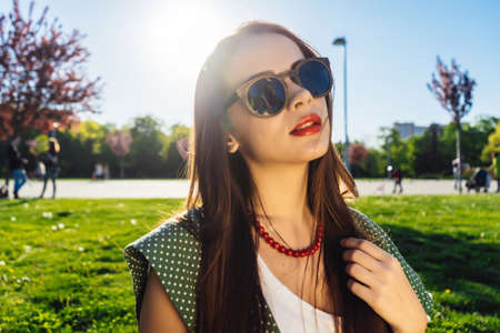 Young beautiful girl in sunglasses walking in the park on a sunny day, enjoying natureの写真素材