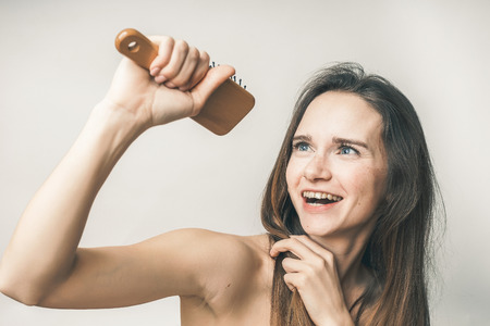 A young girl is happily looking at the comb in her hand, smiling. Isolated on white backgroundの写真素材