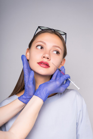 Hands doctor to prick a girl hyaluronic acid in the face.の写真素材