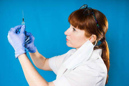 The doctor picks up the medicine in the syringe, looks carefully at the needle,glassesの写真素材