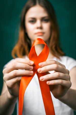 Girl holding a red ribbon in the fight against cancer.の写真素材