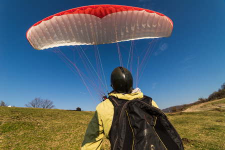Rear view, a paraglider pilot raises the wing into the airの写真素材