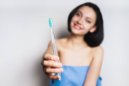 A teenage girl holding a toothbrush in her hands and smiling