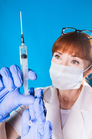 A woman doctor takes the medicine in a syringe and looks carefully at the needle, isolatedの写真素材