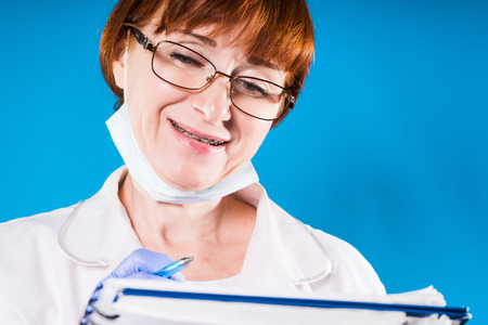 Woman doctor with braces on teeth writing prescriptionの写真素材