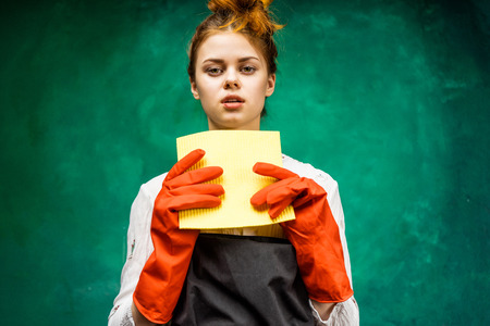 Surprised girl cleaning woman holding a rag in her hands, wearing gloves. Hatesの写真素材