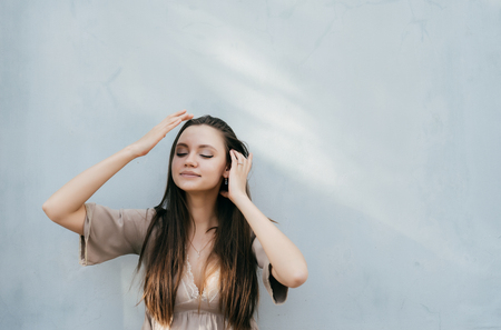 A girl enjoys the weather on a blue background, touches her hairの写真素材