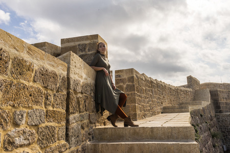 Young beautiful woman posing near an ancient wallの写真素材