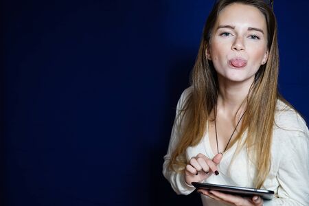 Young girl with a tablet pc in her hands shows a tongue