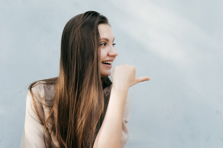 girl with long hair smiles and points her finger to the sideの写真素材