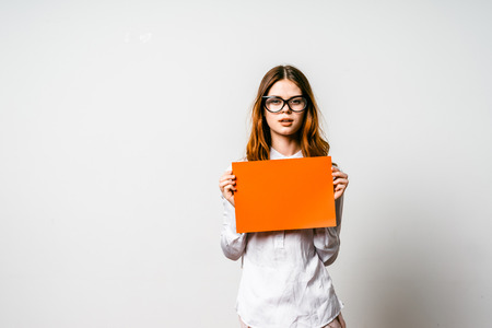 a young girl with glasses is holding an orange file in front of herの写真素材