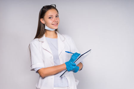smiling pleasant girl in medical gown records patient dataの写真素材
