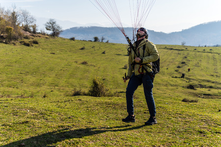 a young man in tourist clothes in nature is going to fly on a parachuteの写真素材