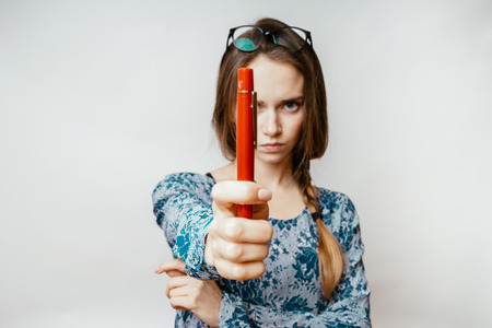angry beautiful girl holding a pen in her hand, close-upの写真素材