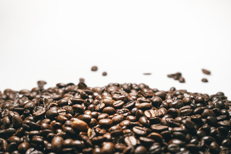 brown coffee beans close-up on a white background, falling grainsの写真素材