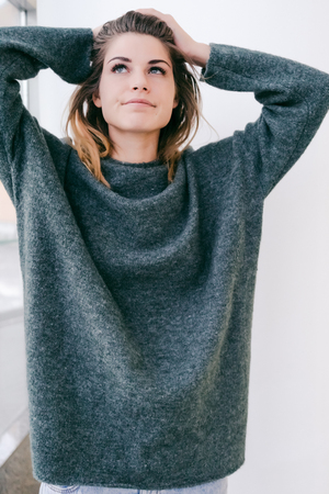 smiling girl in a big dark sweater looked upの写真素材
