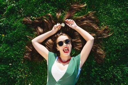 Surprised funny woman enjoying life on grass,happy smile,relax on streetの写真素材