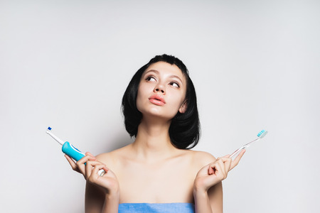 girl with short black hair after a shower chooses which brush to brush your teethの写真素材