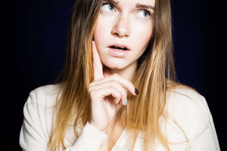 beautiful girl with long hair looking away thoughtfully, isolated on blue background