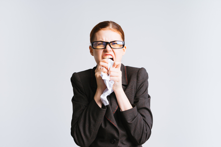 an angry girl with glasses is ready to tear up a piece of paper in her handsの写真素材