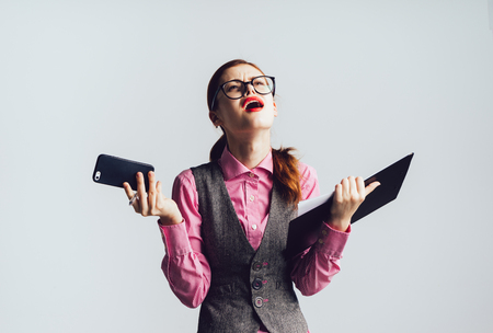 business young girl holding a folder and phone and looks disappointed and angryの写真素材