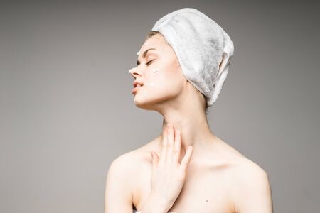 girl with white towel on her head puts cream on faceの写真素材