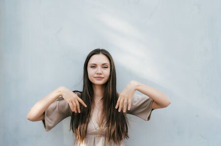 girl with long hair stands against the gray wall and posesの写真素材