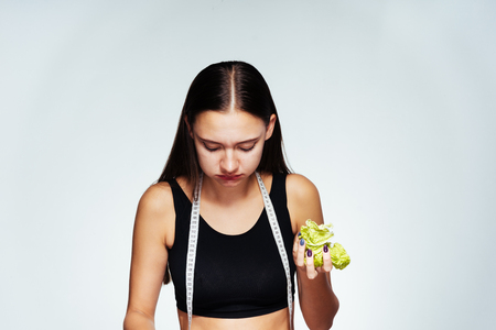 the girl in a sport short shirt is eating cabbage and looking down, sports body, delicious healthy foodの写真素材