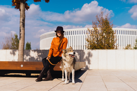 young red-haired girl smiling, sitting on a wooden bench with her dogの写真素材